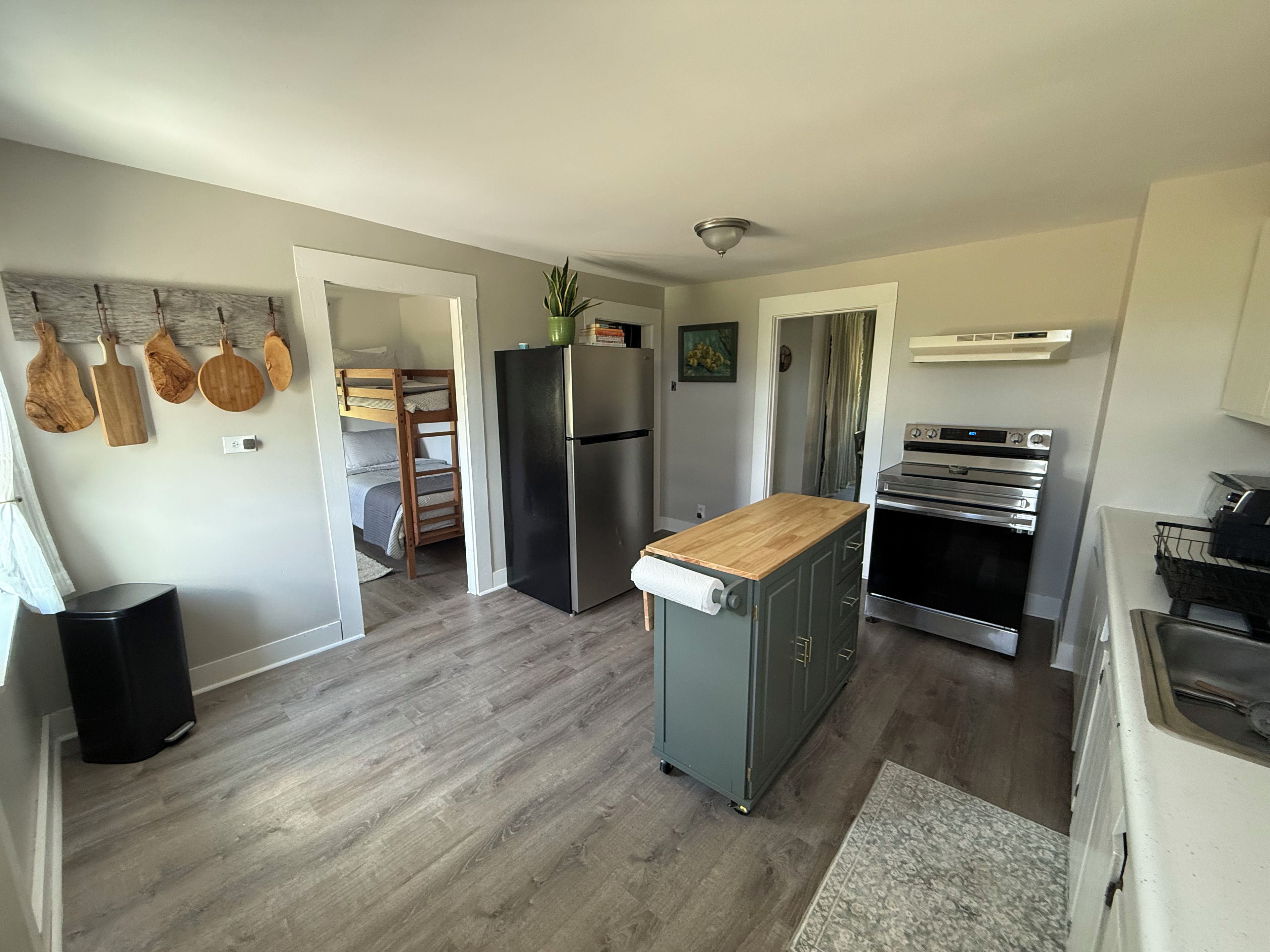 A modern kitchen with a built-in oven, a refrigerator, and a wooden countertop.