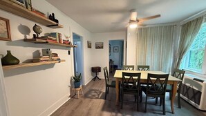A dining area with a table and chairs, a ceiling fan, and a window with curtains.