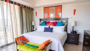 Una habitación de hotel con una cama grande, mesitas de noche, un tocador y un armario, además de una ventana con cortinas.