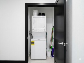 Ett litet och praktiskt tvättrum med tvättmaskin och torktumlare, en mopp och en sopkvast.
