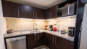 Una cocina moderna con armarios de madera oscura, electrodomésticos de acero inoxidable y encimera de granito.