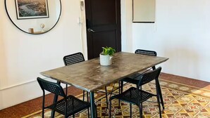 A conference room with a tiled floor, a table with chairs, a potted plant, and a framed picture on the wall.