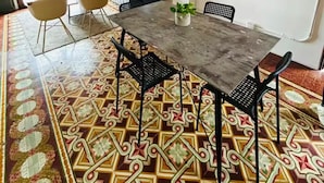Un comedor con una mesa, sillas, una planta en maceta y un espejo redondo en la pared.