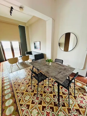 A dining area with a table, chairs, a potted plant, and a round mirror on the wall. - La Botica, Casa Donovan (Panamá)