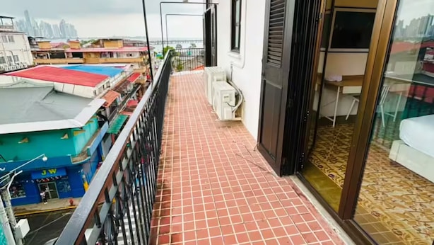 A balcony with a tiled floor, a metal railing, and a view of a cityscape.