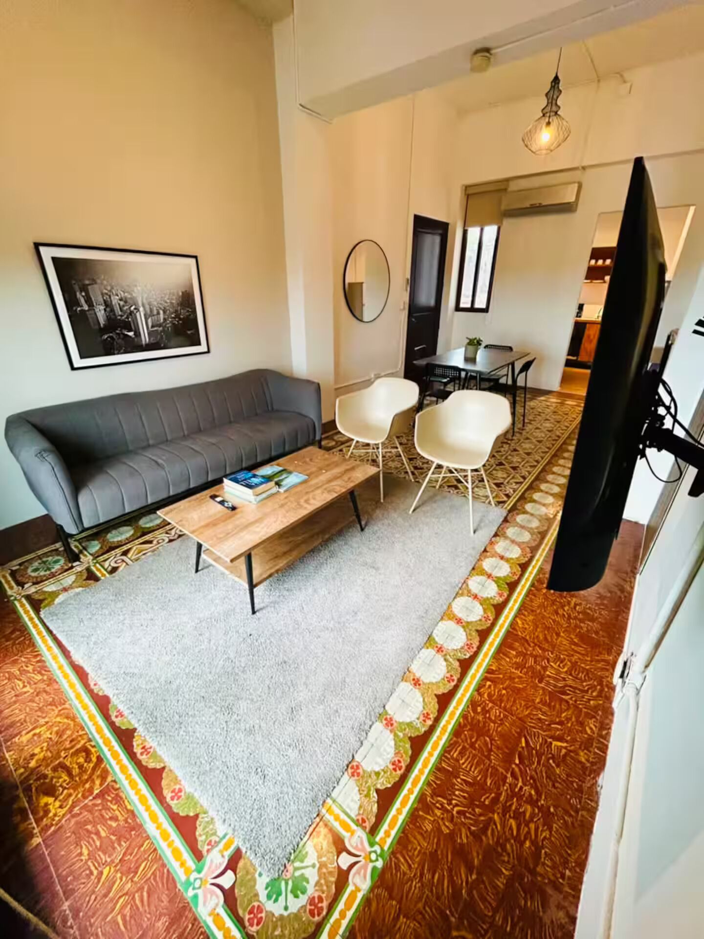 A living room with a sofa, coffee table, two chairs, a dining table, and a television.