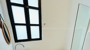 Un baño pequeño con un lavamanos, inodoro y una ventana con persianas.