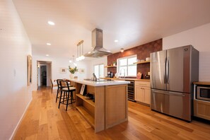 A modern kitchen with a central island, stainless steel appliances, and wooden flooring. - Modern Mesa Retreat Pool Near Gilbert & US-60 (Mesa)
