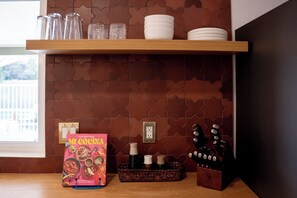 A kitchen counter with a book, a knife block, and a shelf with glasses and plates. - Modern Mesa Retreat Pool Near Gilbert & US-60 (Mesa)