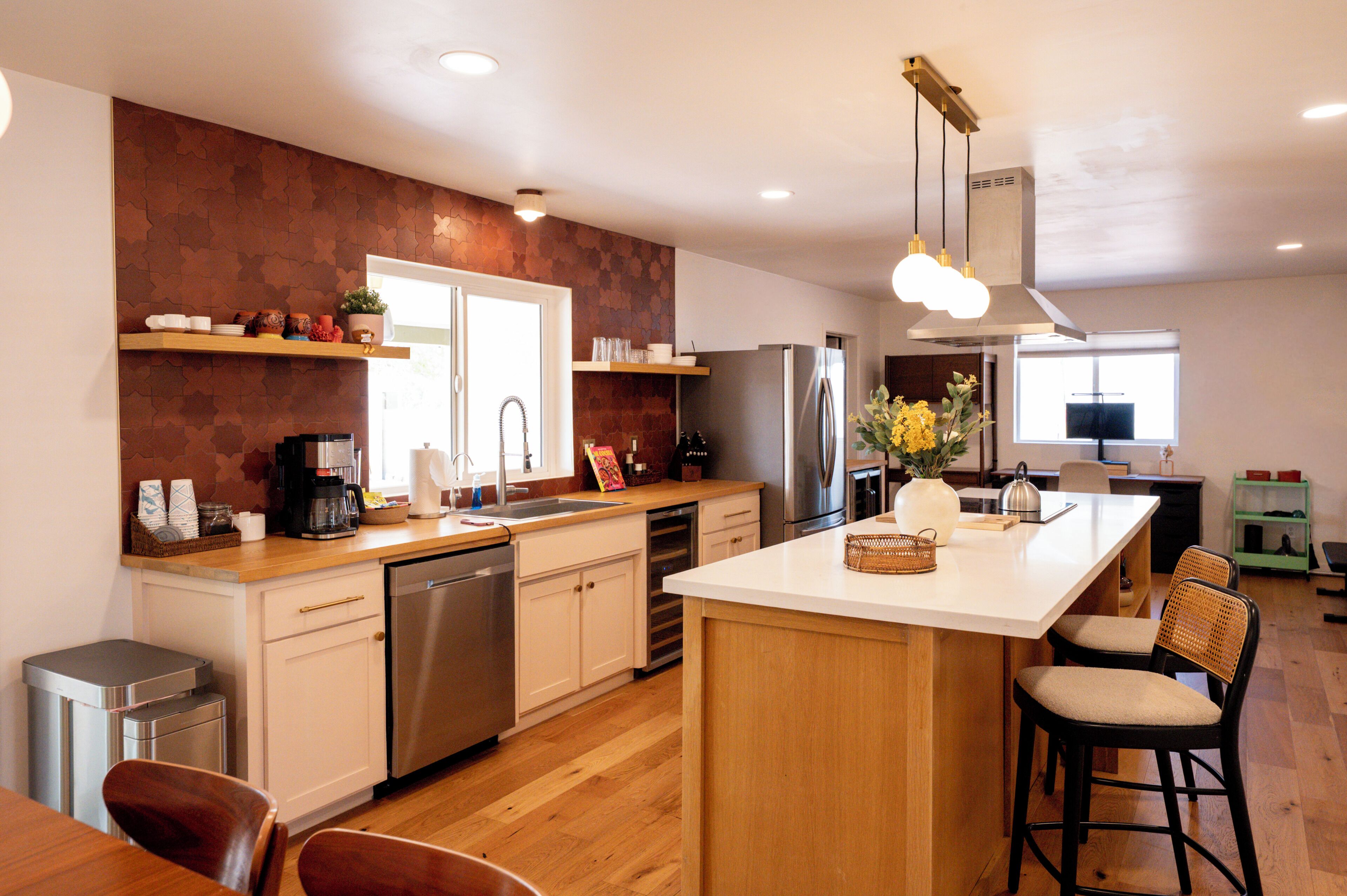 A modern kitchen with a central island, stainless steel appliances, and a wooden backsplash.