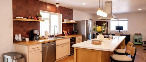 Una cocina moderna con una isla central, electrodomésticos de acero inoxidable y un protector de salpicadero de madera.
