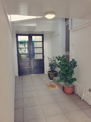 A hallway with a dark wooden door, potted plants, and a tiled floor. - ☼ The Charm of Baulois: Villa Passiflore ☼ (La Baule-Escoublac)