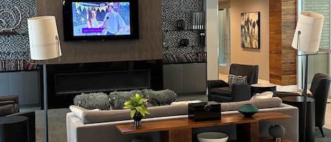 A modern living room with a flat-screen TV, sofas, a coffee table, and a fireplace.
