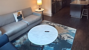A modern living room with a sofa, a coffee table, and abstract wall art. - Preston Royal Single II I Premium 1BR in Dallas (Dallas)
