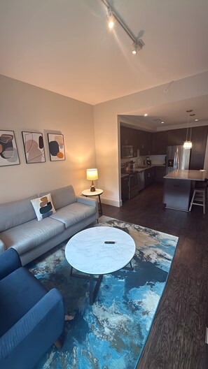A modern living room with a sofa, a coffee table, and abstract wall art. - Preston Royal Single II I Premium 1BR in Dallas (Dallas)