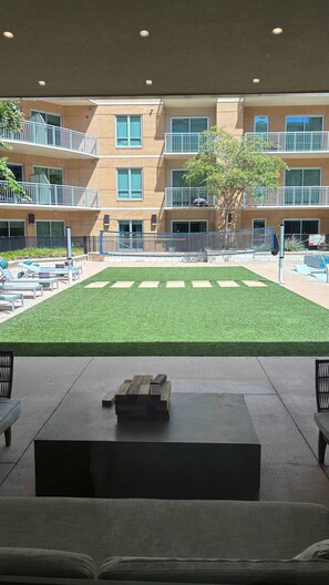 A courtyard with artificial grass, lounge chairs, and a concrete table. - Preston Royal Single II I Premium 1BR in Dallas (Dallas)