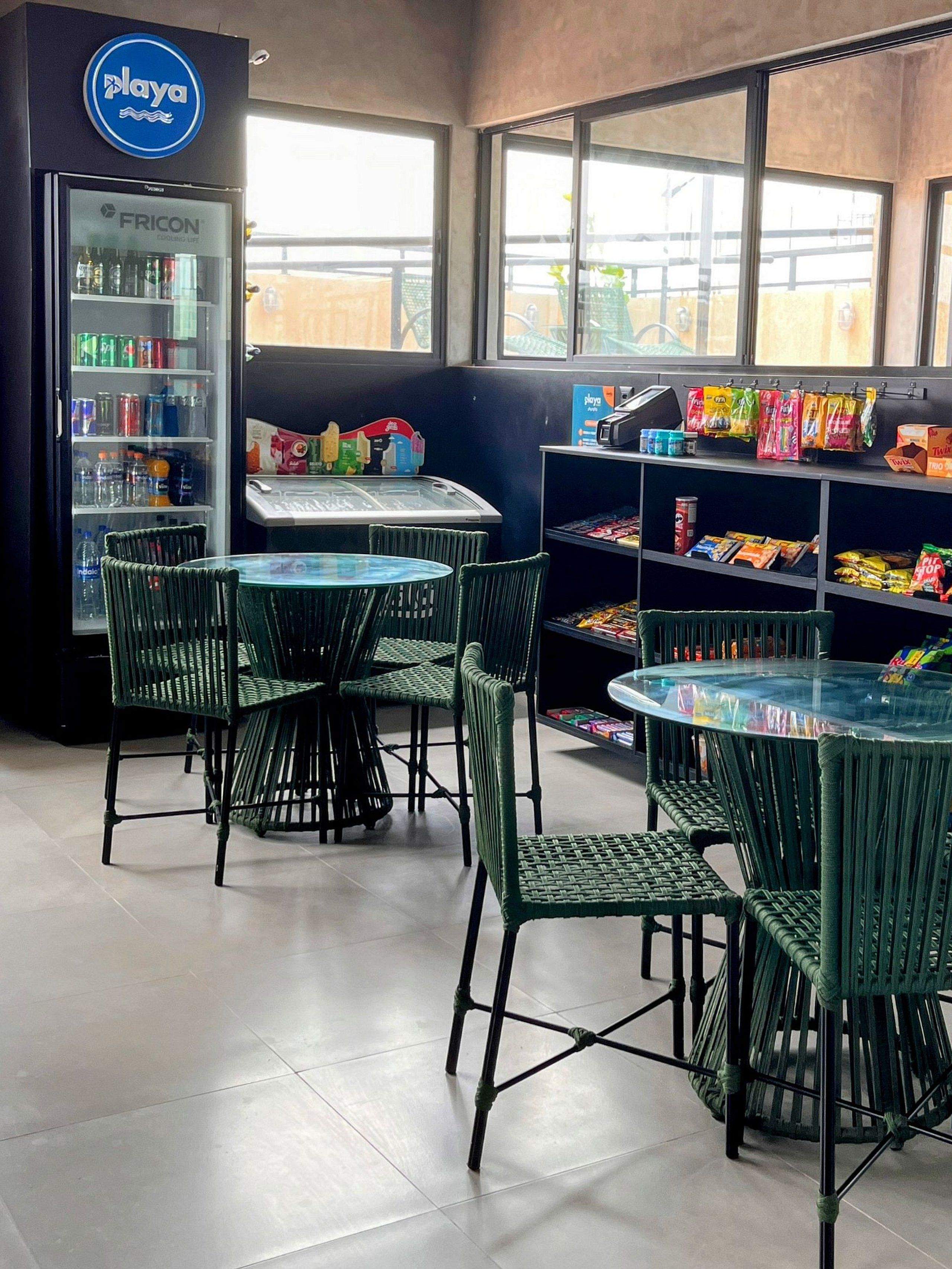 Un espace détente avec des tables et des chaises, un distributeur automatique et des étagères remplies d’en-cas.