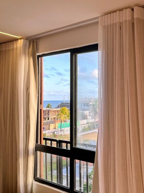A window with a view of a coastal cityscape, including buildings and a bridge.