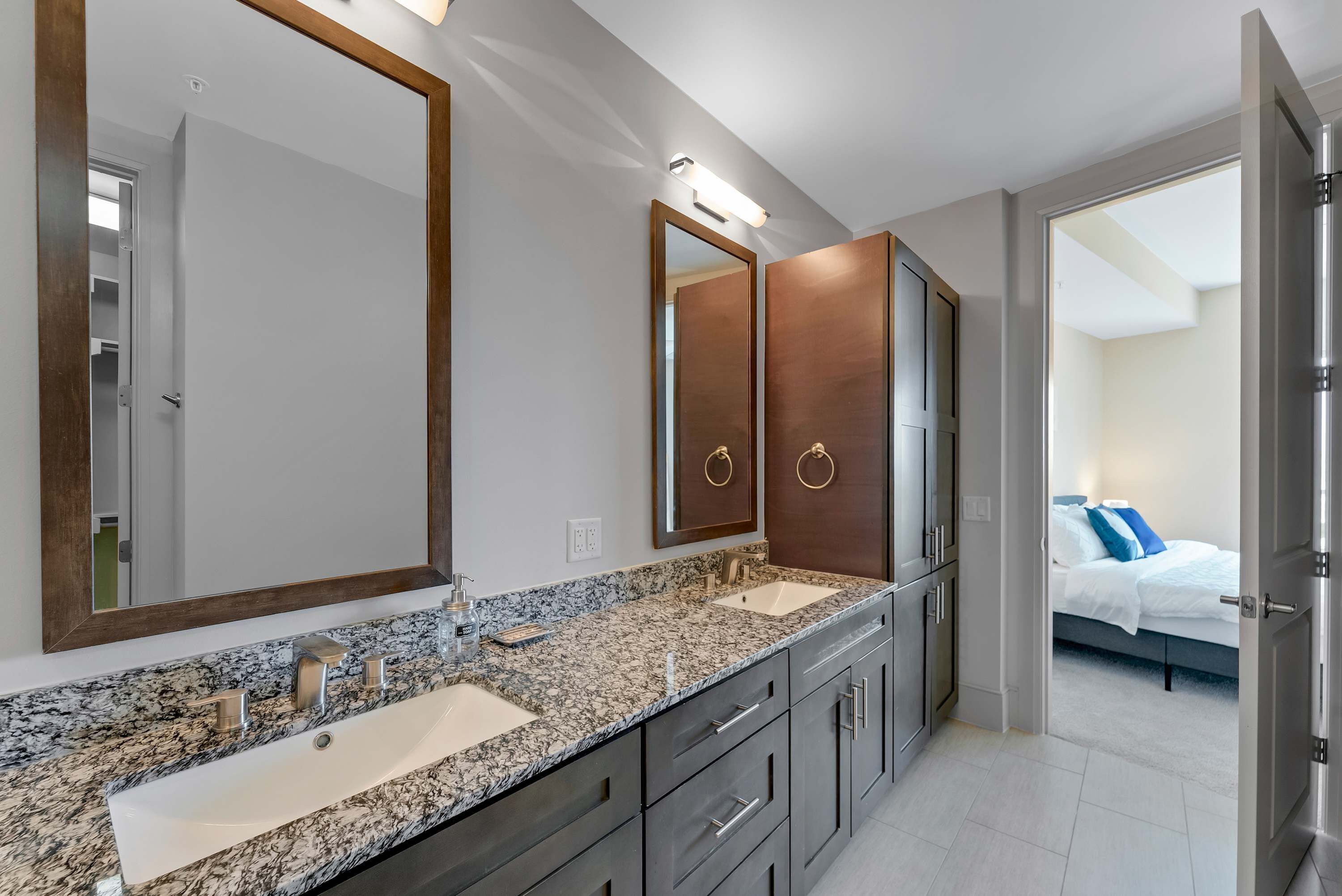 Une salle de bain moderne avec deux vasques, un grand miroir et un dressing.