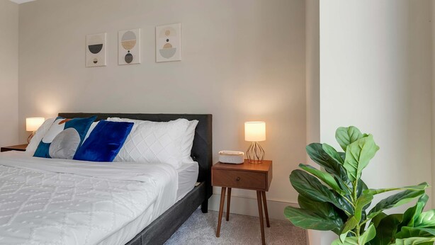 A hotel room with a bed, bedside lamps, a nightstand, and wall art. - Preston Royal Double I Premium 2BR in Dallas (Dallas)