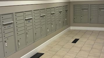 A row of U.S. Mail lockers with a tiled floor and recessed lighting.