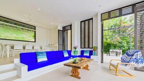 A modern living room with a blue sofa, wooden coffee table, and a dining area with white chairs. - Tremendous 4-bedroom house in Anapoima perfect for your getaway (Anapoima)