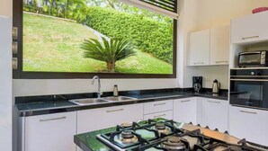 A modern kitchen with a gas stove, a sink, and a window overlooking a garden. - Tremendous 4-bedroom house in Anapoima perfect for your getaway (Anapoima)
