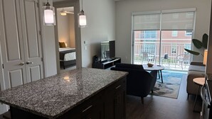 Una cocina moderna con encimeras de granito, un comedor con mesa y sillas, y un balcón con vistas al exterior.