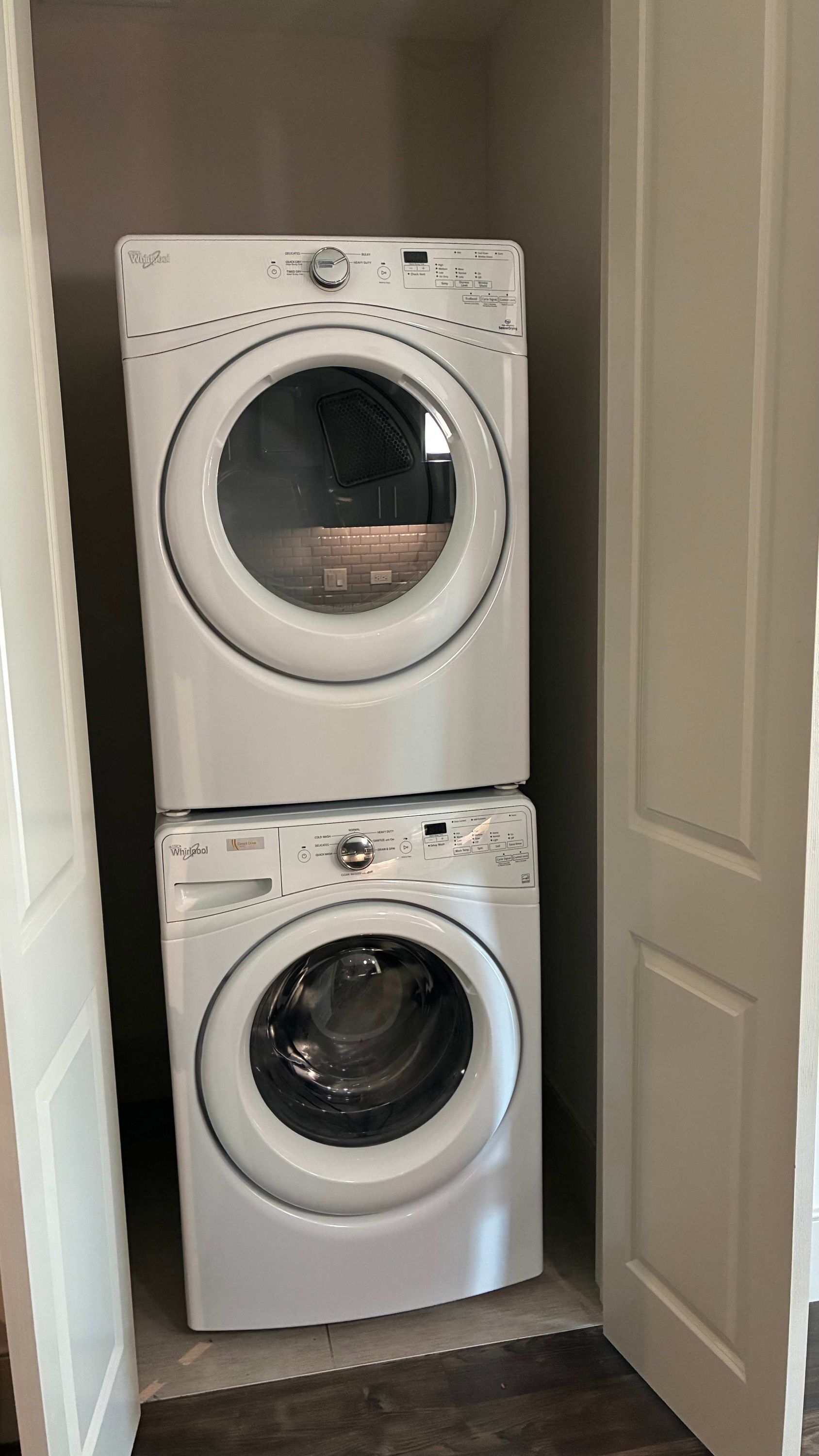 A compact laundry room with two stacked Whirlpool front-loading washing machines.