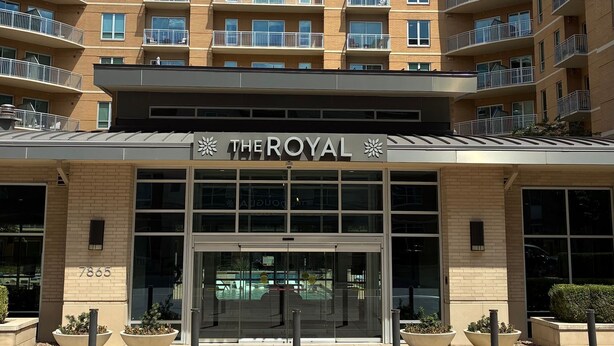Un hotel de varios pisos con una entrada destacada, balcones y cielo despejado.