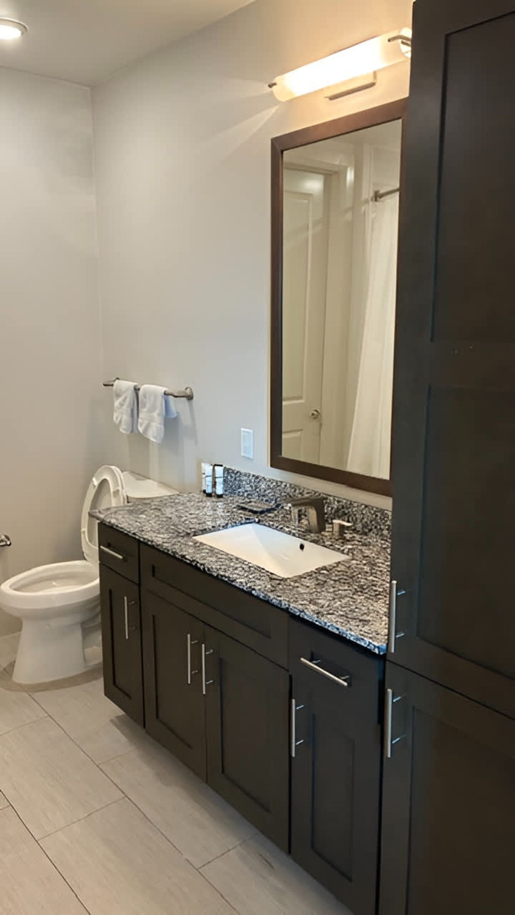 A bathroom with a toilet, sink, and mirror.
