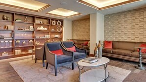 Ein modernes Wohnzimmer mit einer Couch, zwei Sesseln, einem Couchtisch und einem Bücherregal voller Dekoration.