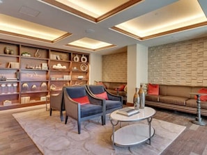 A modern living room with a sofa, two armchairs, a coffee table, and a bookshelf filled with decorative items. - Preston Douglas Single I Premium 1BR in Dallas (Dallas)