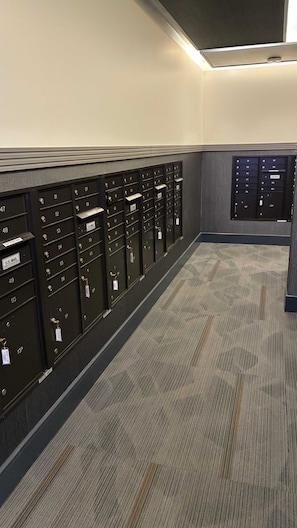 A row of mailboxes with labels and keys, a carpeted floor, and a wall with a textured finish. - Preston Douglas Single I Premium 1BR in Dallas (Dallas)