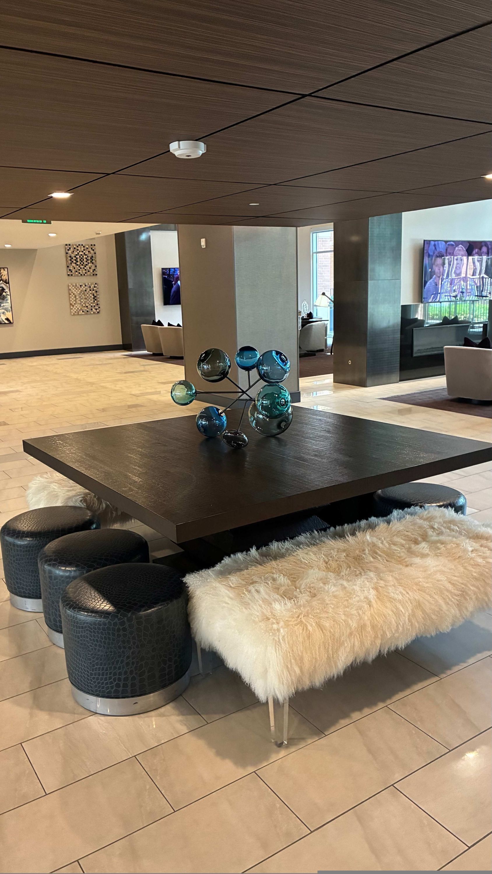 Un hall d’entrée moderne avec une table centrale, un banc moelleux et une sculpture en verre décorative.