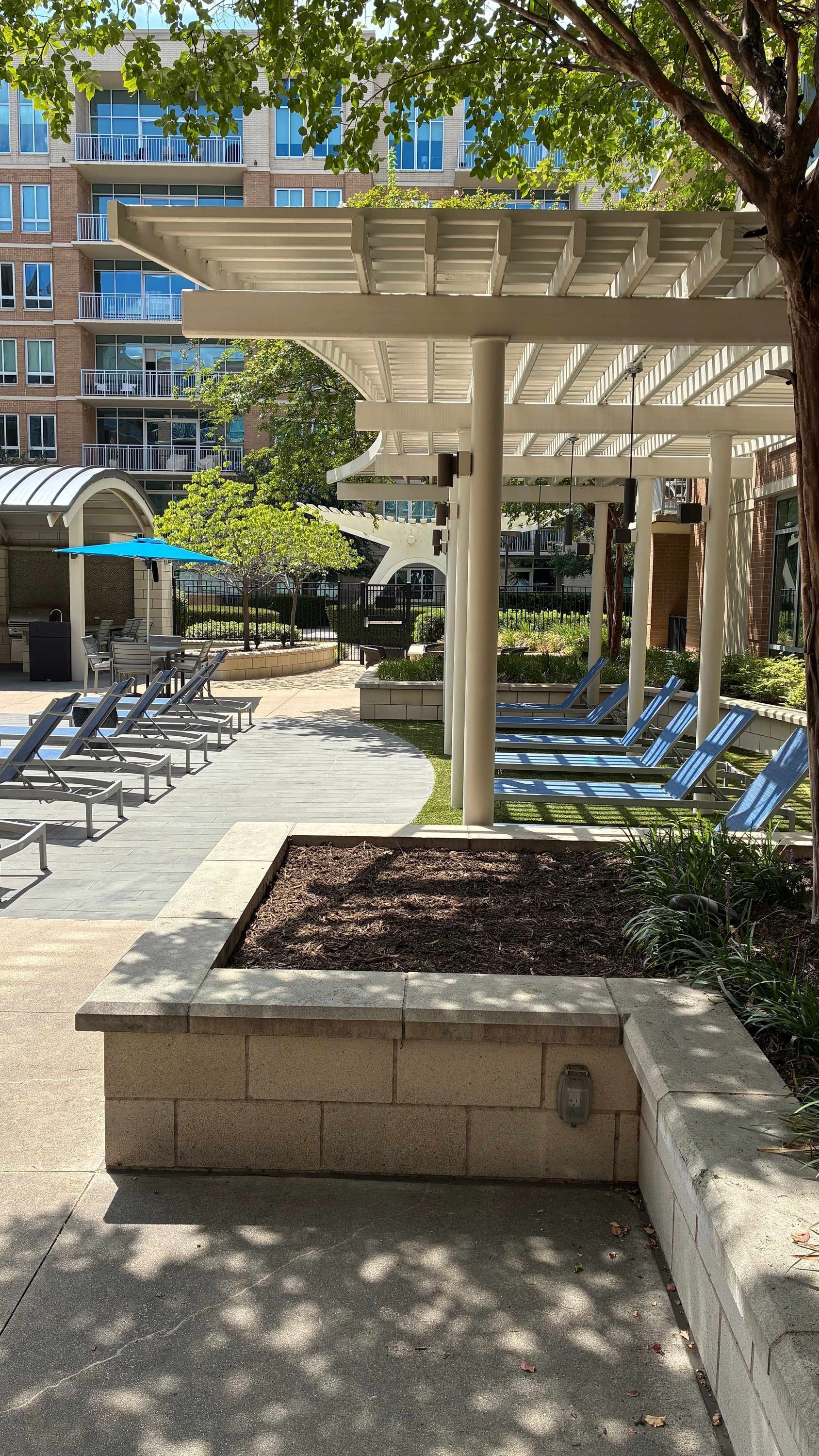A covered outdoor area with lounge chairs and a pool.