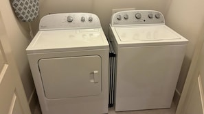 Two white Whirlpool washers in a laundry room with a patterned wall decoration. - Preston Douglas Double I Premium 2BR in Dallas (Dallas)