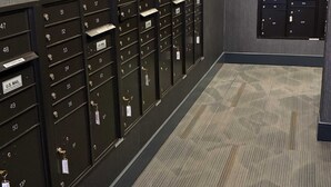 A row of mailboxes with labels and keys, a carpeted floor, and a wall with a textured finish. - Preston Douglas Double I Premium 2BR in Dallas (Dallas)