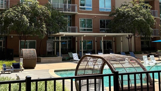 A multi-story residential building with balconies, a swimming pool, and outdoor seating. - Preston Douglas Double I Premium 2BR in Dallas (Dallas)