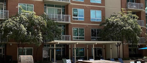Un edificio residencial de varios pisos con balcones, piscina y mobiliario de exterior.