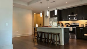 A modern kitchen with dark cabinets, stainless steel appliances, and a central island with bar stools. - Preston Douglas Double I Premium 2BR in Dallas (Dallas)