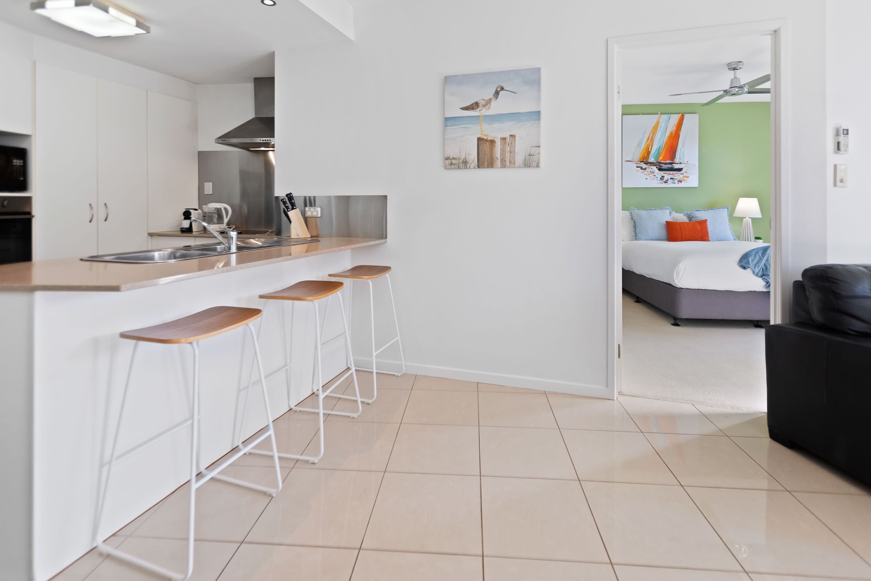 A modern kitchen with a central island, bar stools, and a dining area.