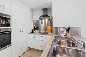 Eine moderne Küche mit Edelstahlgeräten, einem Backofen, einer Mikrowelle, einer Kaffeemaschine und einem Spülbecken.