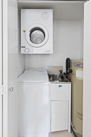 Ein kleiner Waschraum mit einer Waschmaschine mit Frontlader, einem Trockner und einem Waschbecken.