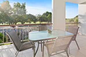 Ein Balkon im Freien mit einem Glastisch und vier Korbstühlen.
