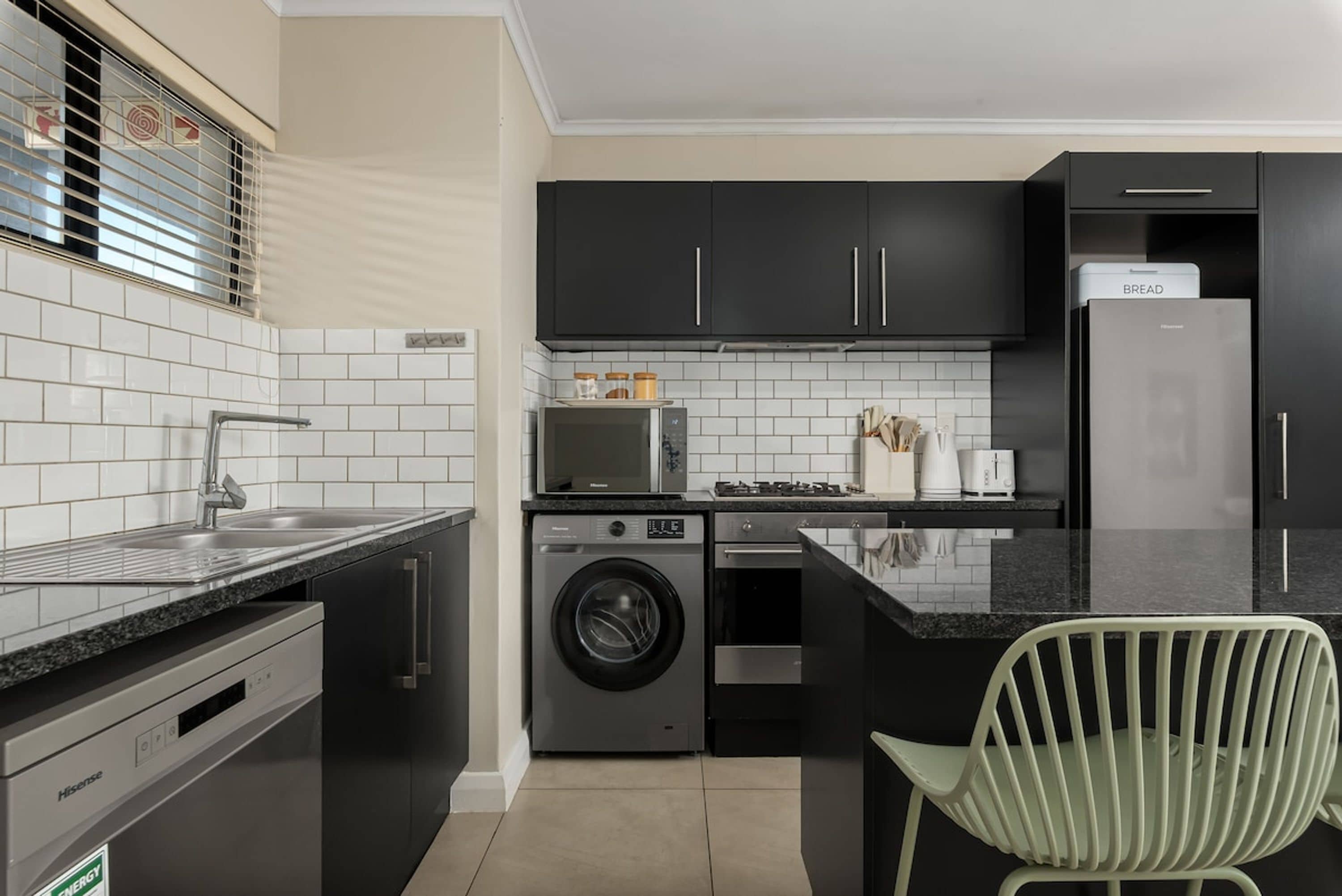 A compact kitchen with a washing machine, a microwave, and a refrigerator.