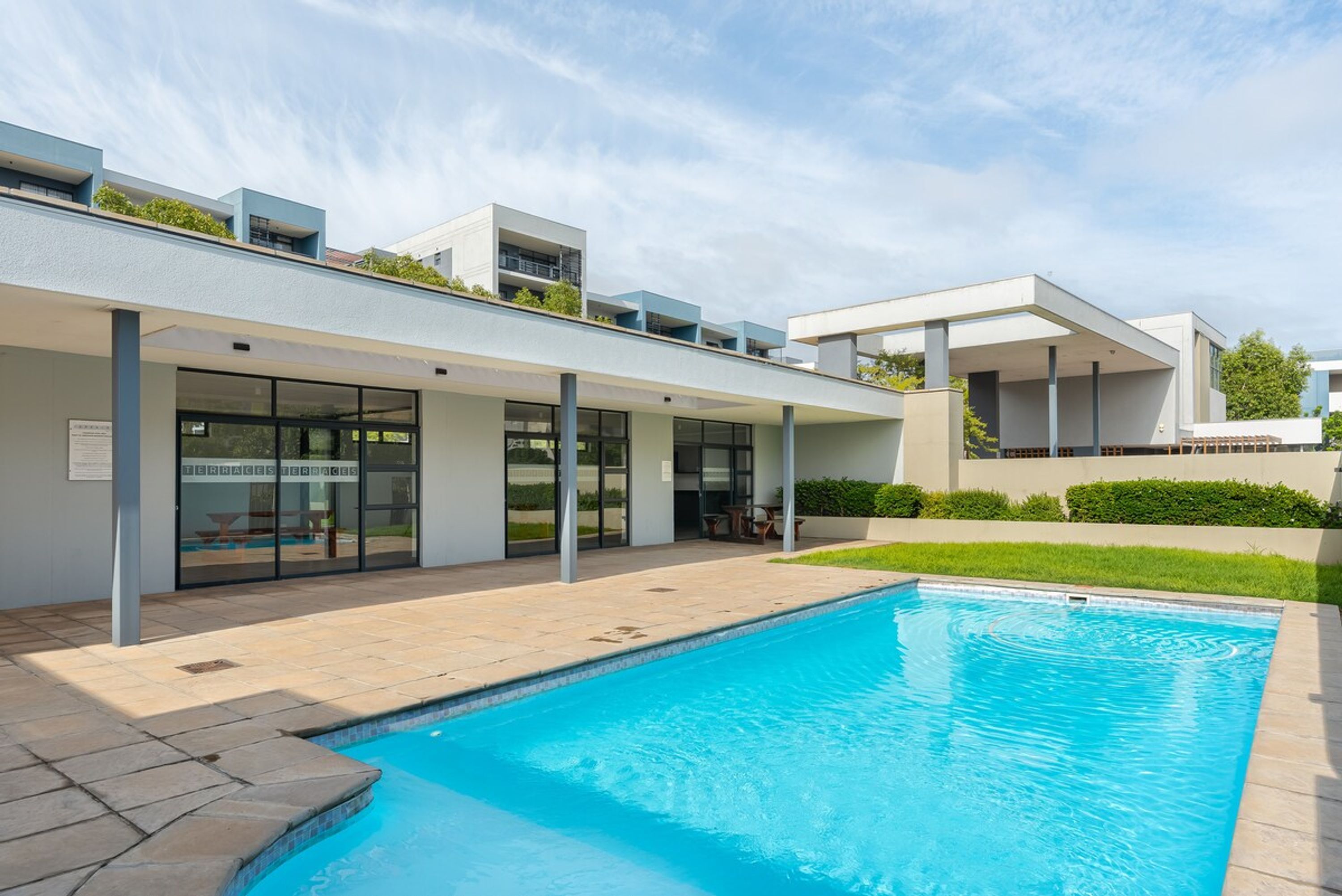 Ein modernes Gebäude mit Schwimmbad, großen Fenstern und einer flachen Dachfläche.