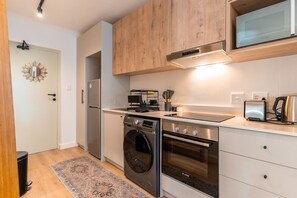 A compact kitchen with a built-in oven, microwave, and a dishwasher. - The Sage Coastal Comfort Convenience (Cape Town)