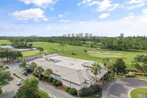 A golf course with a parking lot, a building with a flat roof, and a clear sky. - Over the Dunes at Lost Key Villas (Pensacola)
