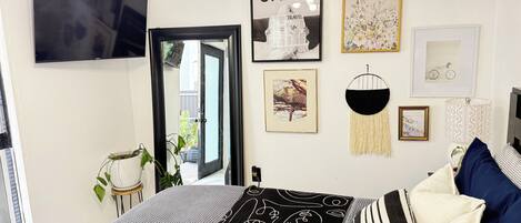 A bedroom with a bed, a television, and various wall decorations including framed pictures and a sign.